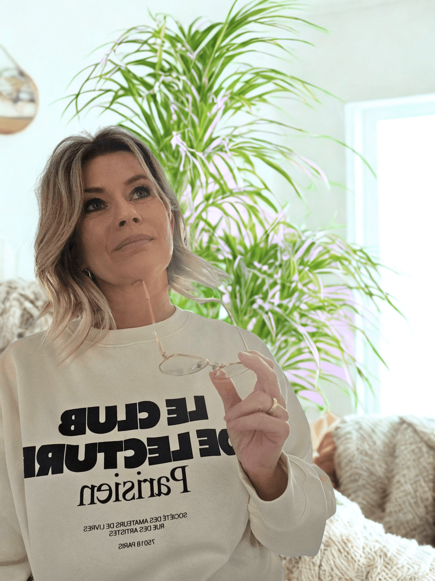 Chantal Degen kijkt nadenkend omhoog met bril in hand in woonkamer
